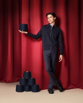 A person standing in front of red curtains holding a dark cylinder